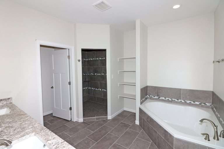 The Rubí primary bathroom with shower and soaking tub, new home by Integrity Homes in Western Colorado