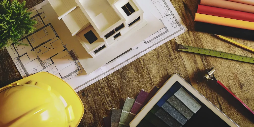 The custom home design and build process with a model house, blueprints, and planning tools.
