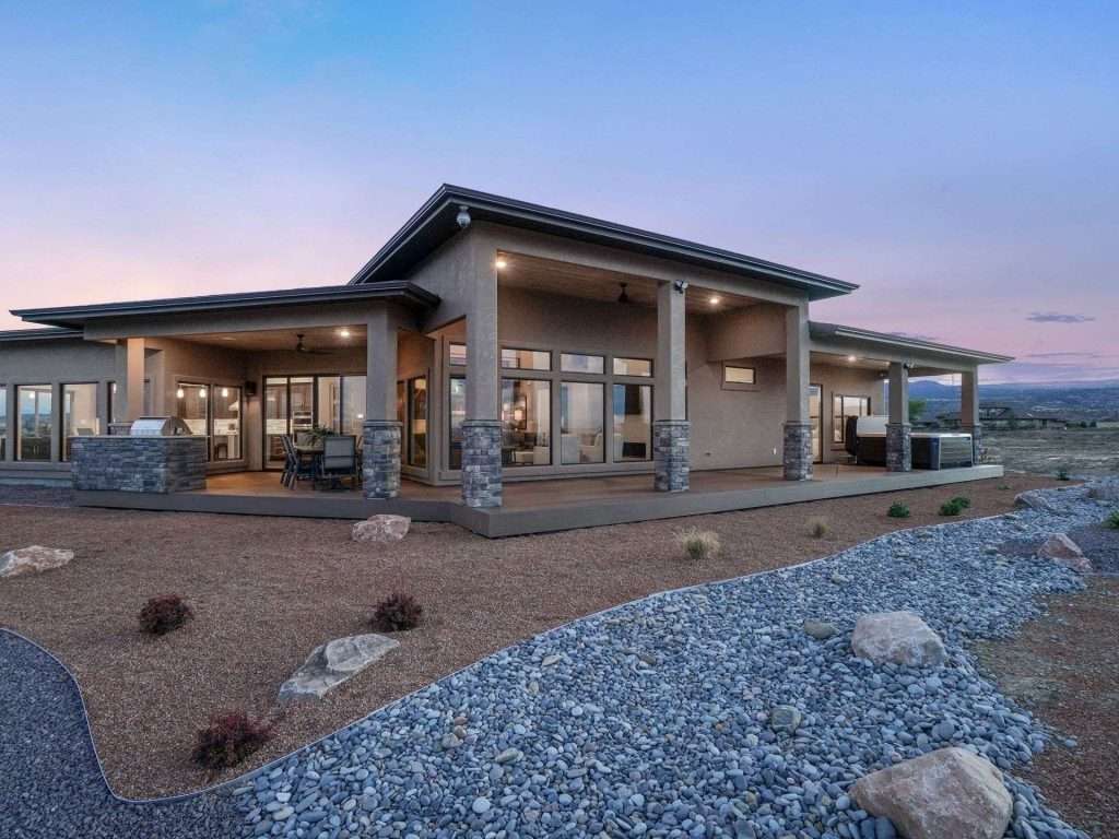 Covered rear patio with an outdoor kitchen at twilight, the award-winning home behind the Gunnison floor plan